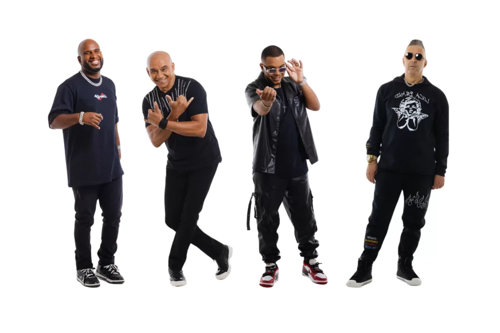 Integrantes do Exaltasamba abraçados no palco durante show ao vivo.