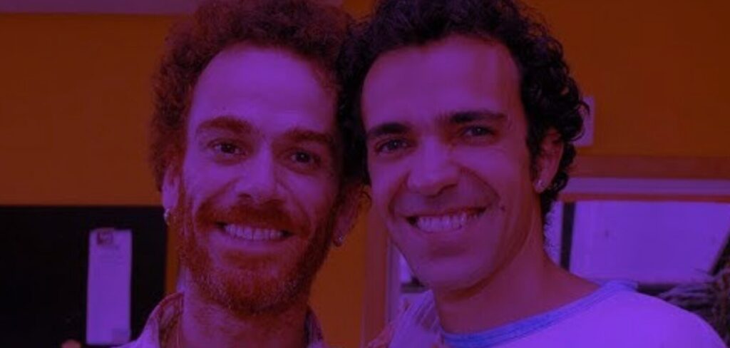 Nando Reis e Paulinho Moska tocando violão juntos no palco.